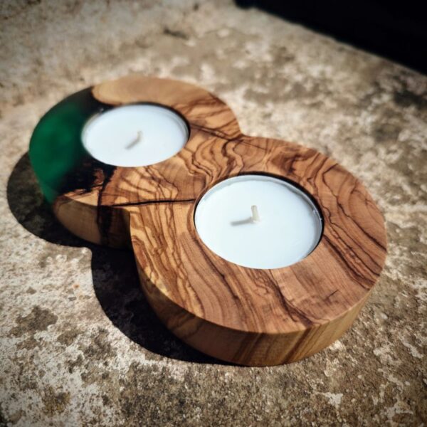 Green epoxy tealight holder resting on a cement wall, showcasing its elegant infinity shape and holding two tealights