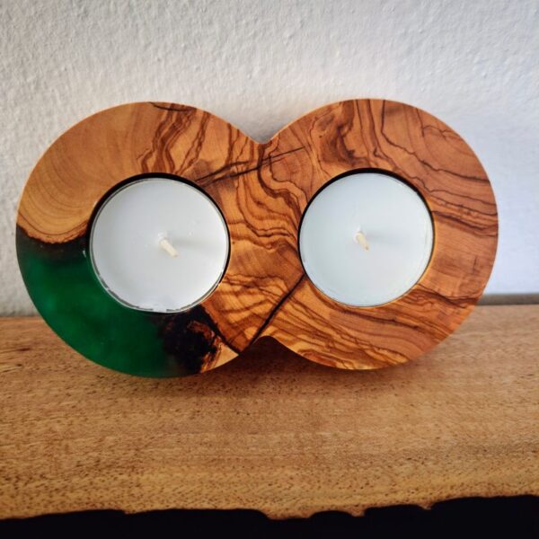 Green epoxy tealight holder in an infinity shape, leaning against a textured wall, holding two tealights